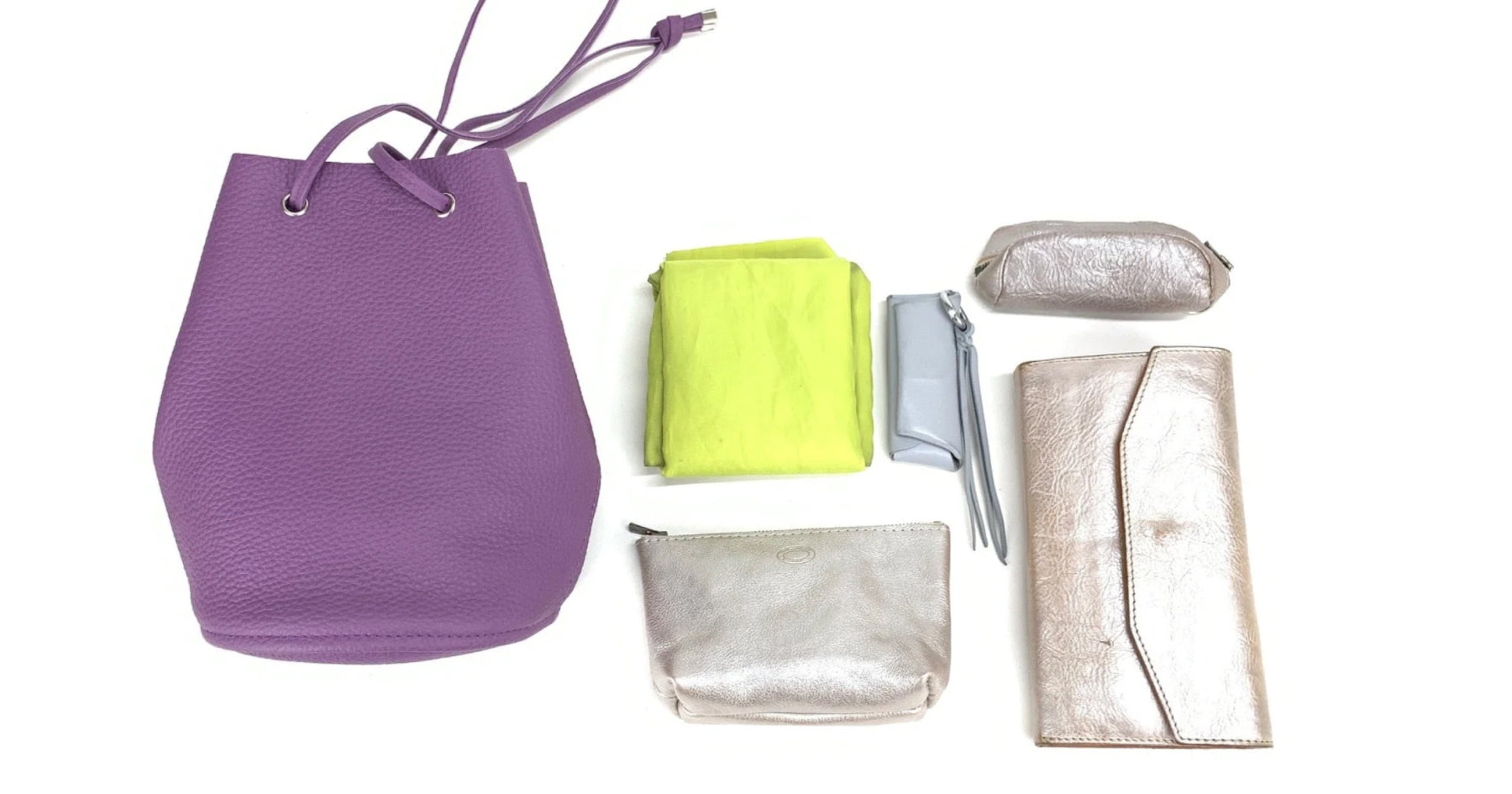 左から紫色の巾着ショルダーバッグ、黄緑色の布、シルバーの小物類が並べられている。