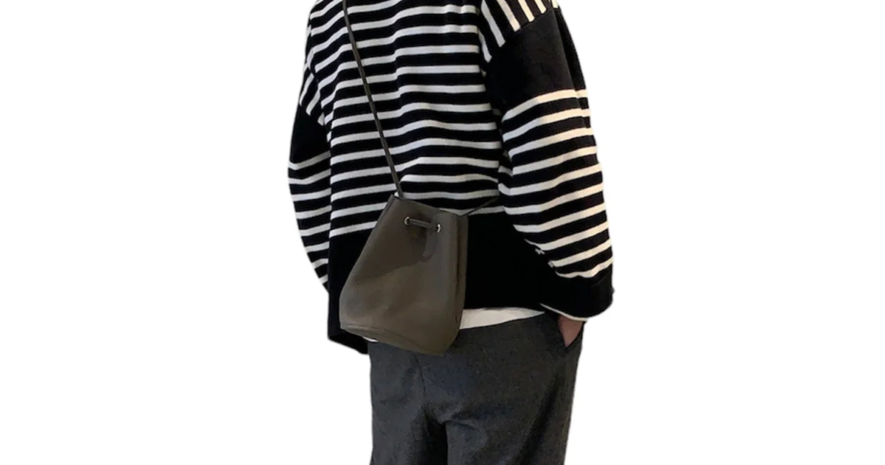 白と黒のボーダートップスを着た人がトープの巾着ショルダーバッグを持っている。